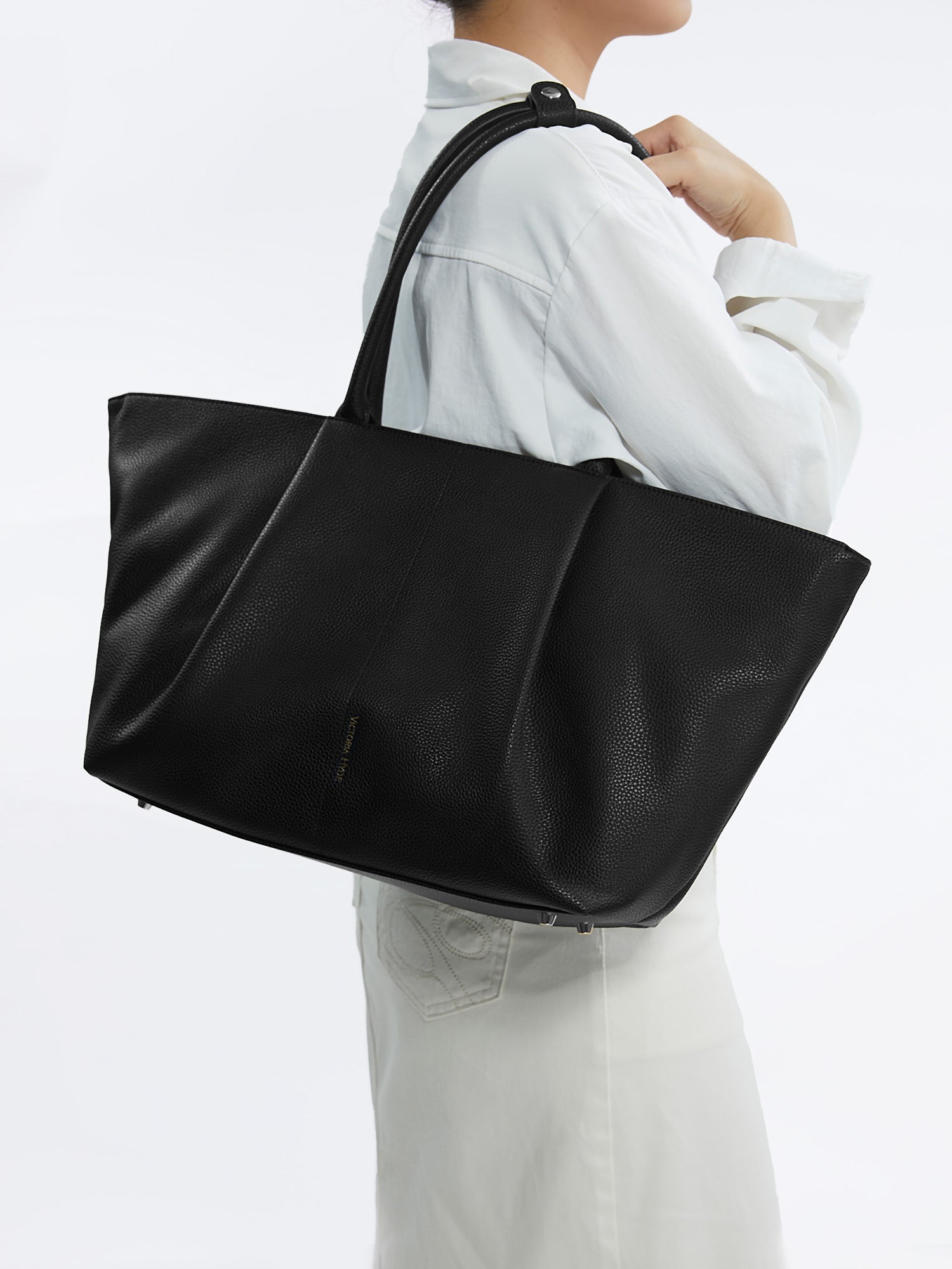 Model carrying the Victoria Hyde Ada Black business laptop bag in brown as a shoulder bag, made of stylish, ergonomic vegan leather.