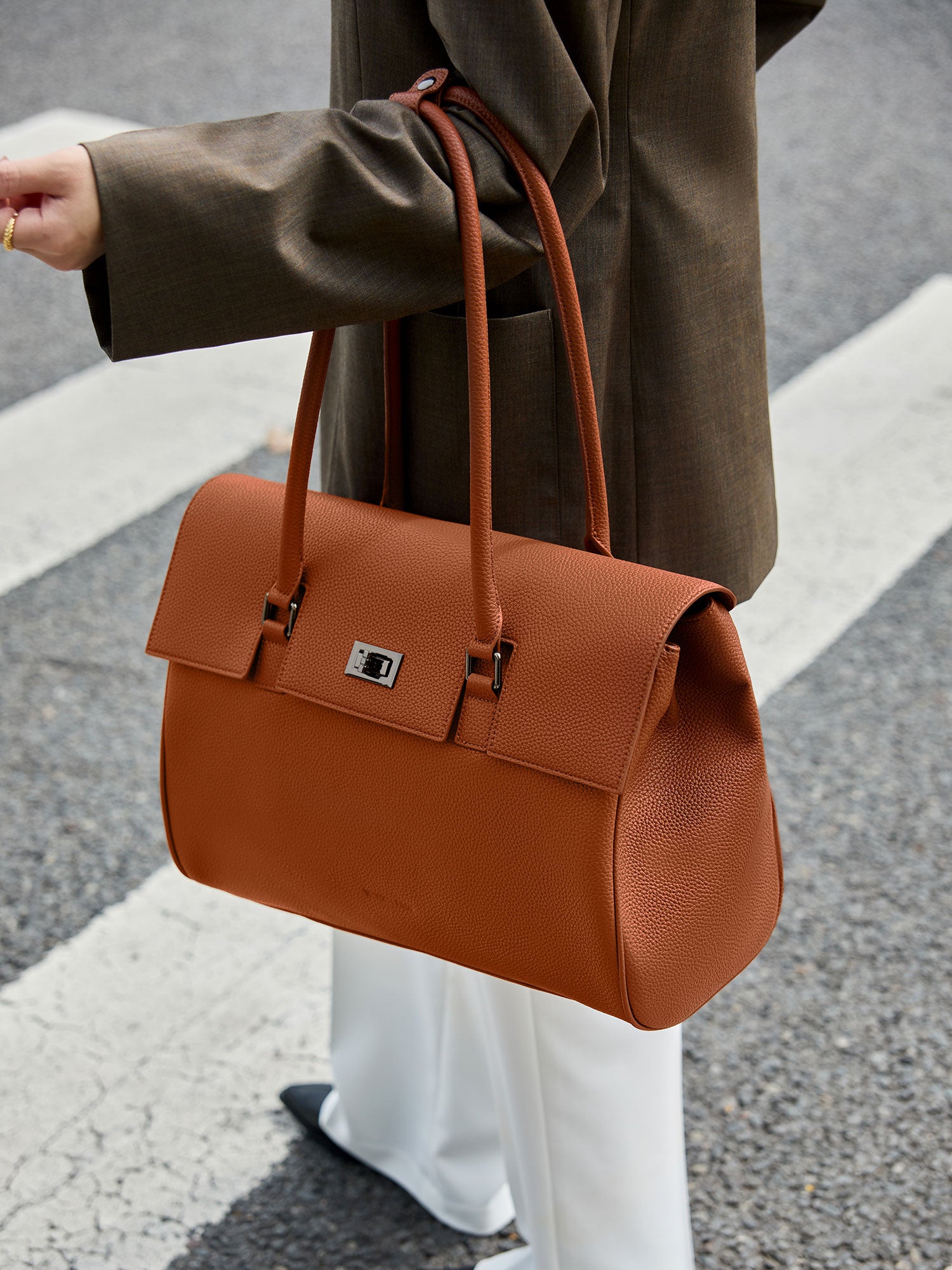 Professional woman carrying the Victoria Hyde Jolene Brown laptop handbag, elegant vegan leather design with 16-inch laptop compartment for office work.