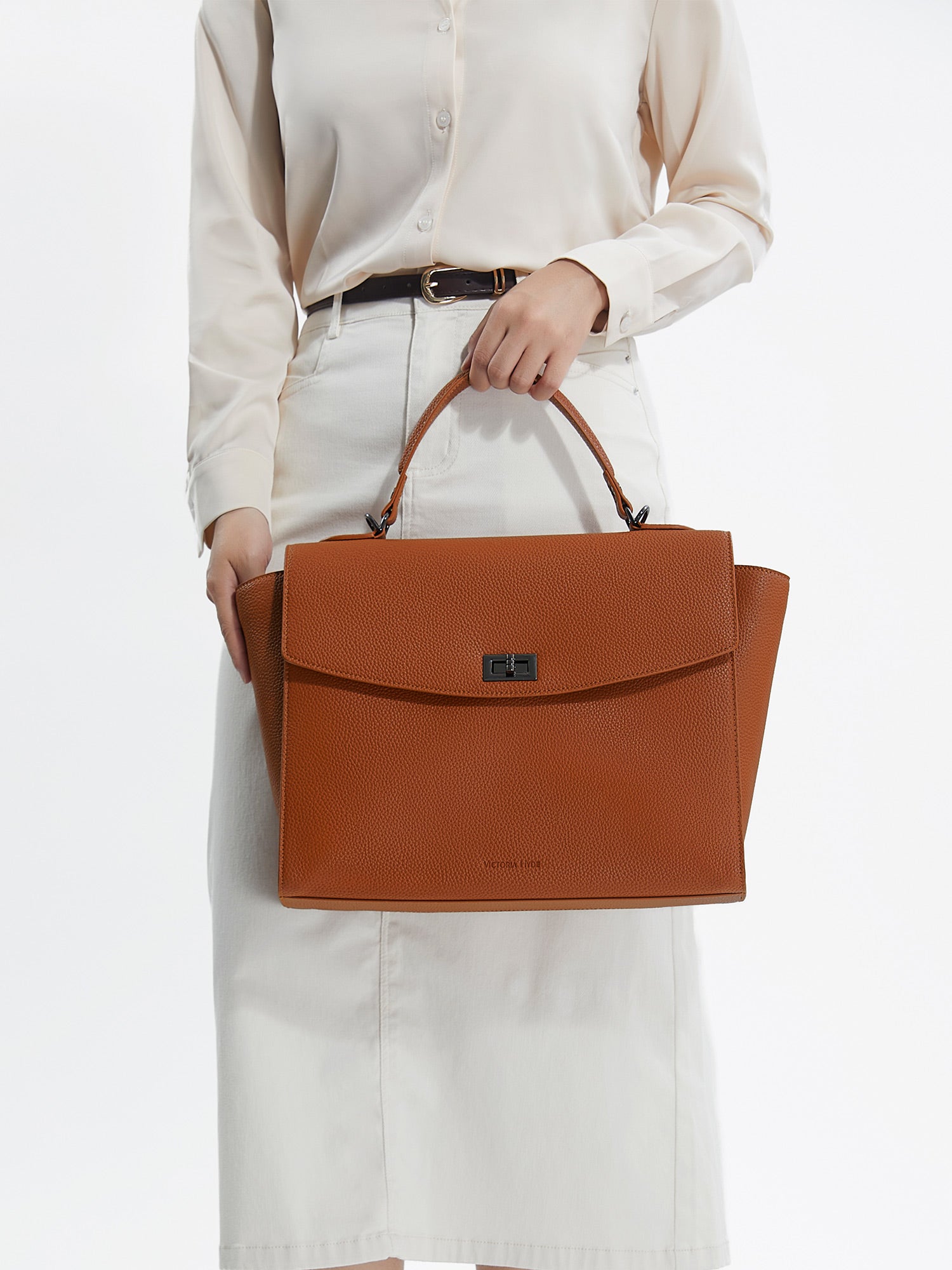 Professional woman carrying the Victoria Hyde Potter Brown laptop handbag, elegant vegan leather design with 13-inch laptop compartment for office work.