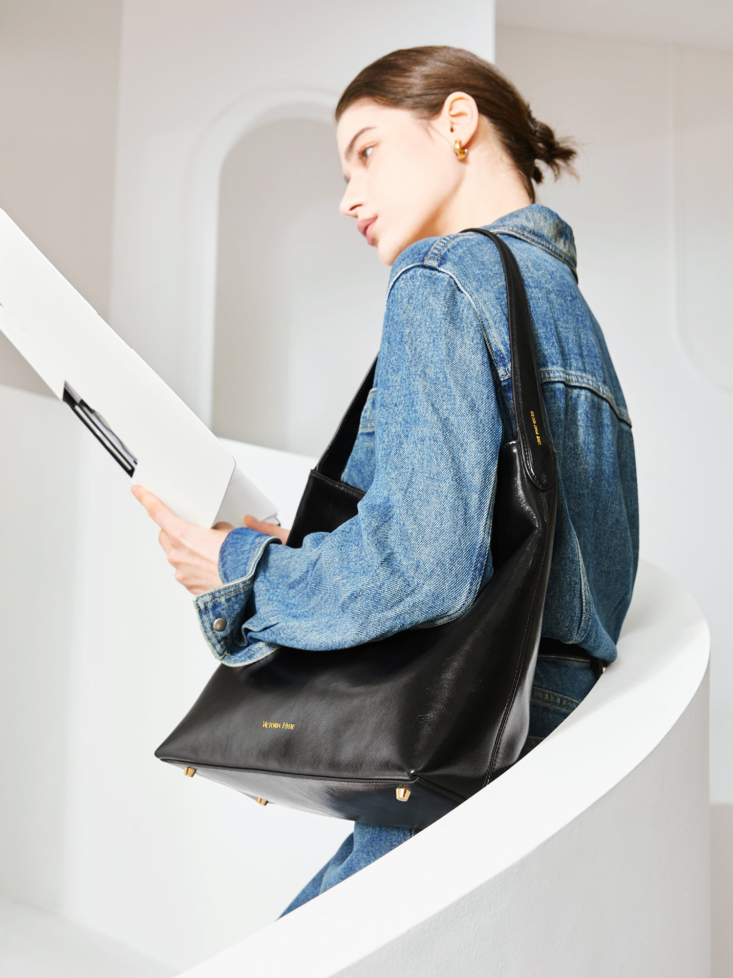 Victoria Hyde shoulder bag in microfiber leather with light gold fittings, padded sunglasses compartment, trolley strap, and inscriptions “Love what you do” and “New Work” for modern dynamic women.