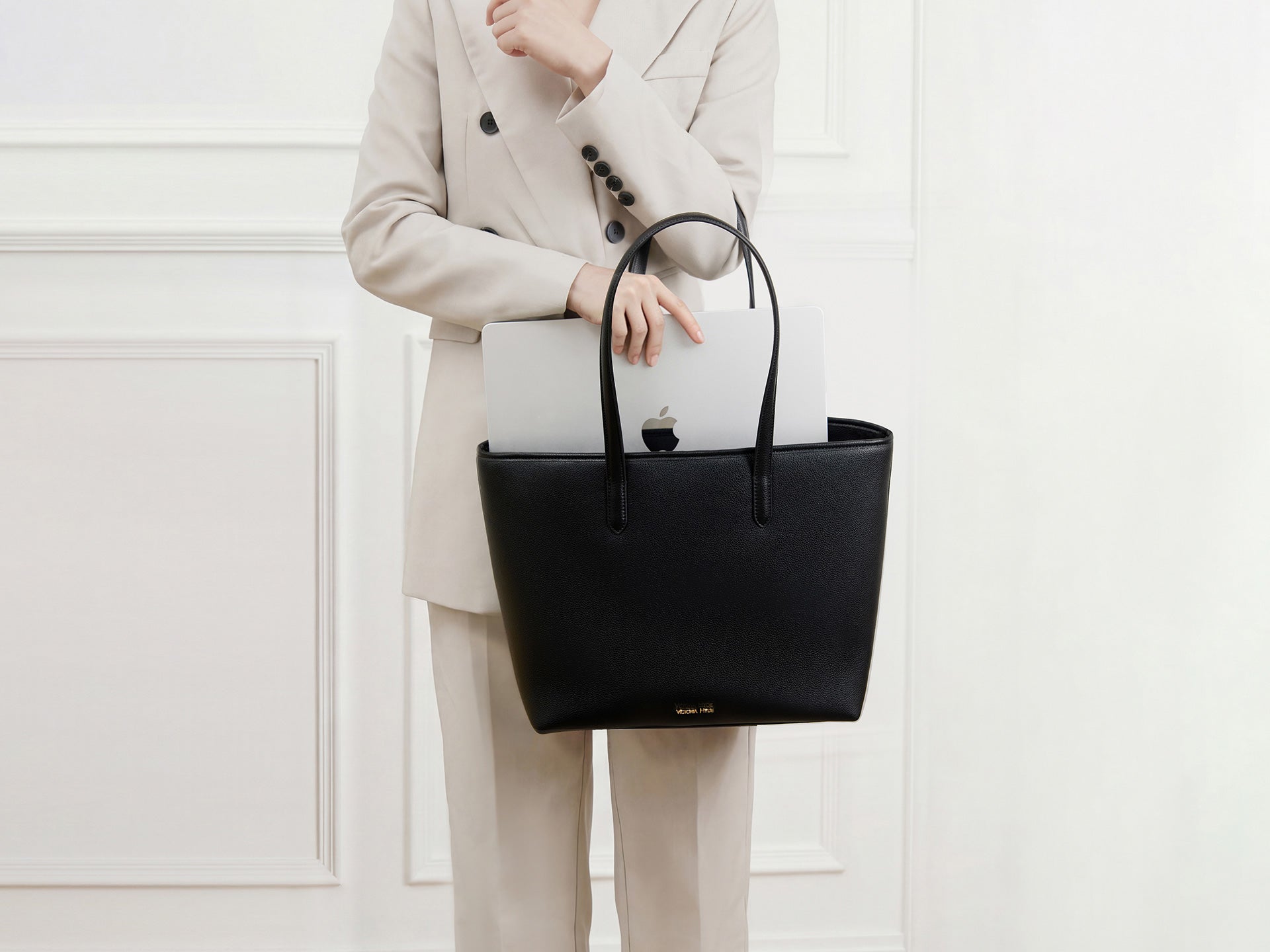 Black Victoria Hyde business tote bag for women. Elegant leather laptop bag for the office featuring a MacBook